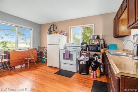 Kitchen featuring electric range, light countertops, light wood finished floors, black microwave, and brown cabinets
