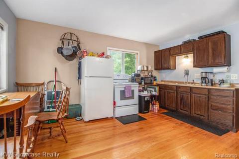 Kitchen with light countertops, white appliances, light wood-style flooring, and dark brown cabinetry
