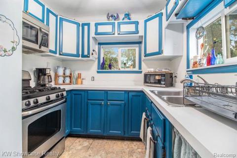 Kitchen featuring blue cabinetry, appliances with stainless steel finishes, and light countertops