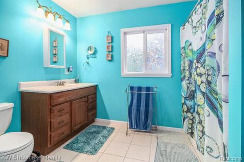 Bathroom featuring light tile patterned floors, vanity, and curtained shower