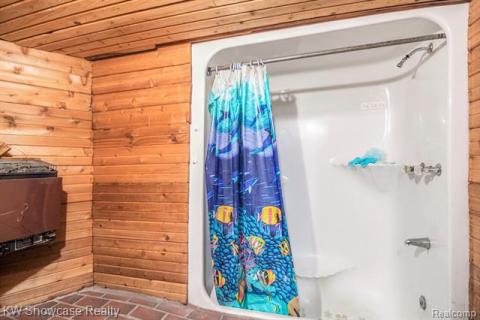 Full bath with wooden walls, a stall shower, and wood ceiling