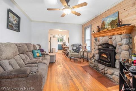 Living room featuring crown molding, hardwood / wood-style flooring, arched walkways, and ceiling fan