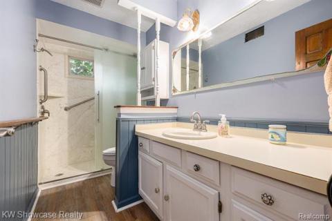 Bathroom with a marble finish shower, vanity, dark wood-style floors, and a textured ceiling