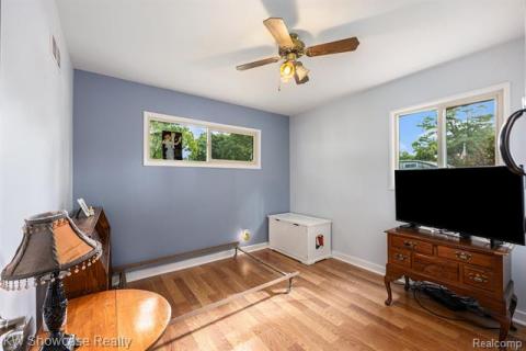 Living area with light wood finished floors, healthy amount of natural light, and a ceiling fan