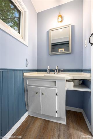 Bathroom with vanity, dark wood-style flooring, and a wainscoted wall