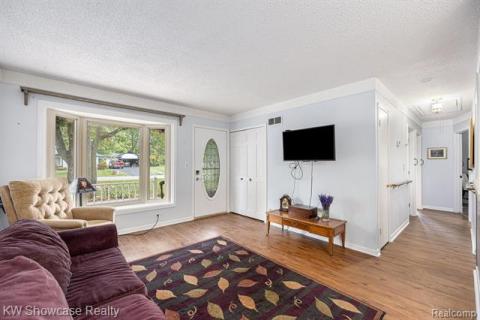 Living room with attic access, light wood-style flooring, and a textured ceiling