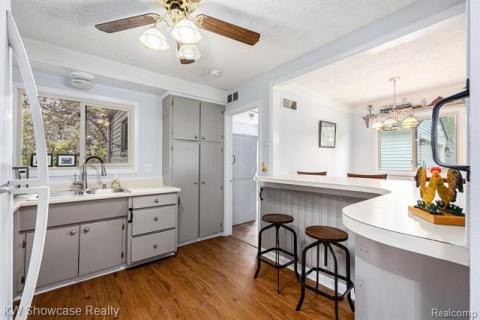 Kitchen featuring a breakfast bar, gray cabinetry, a textured ceiling, dark wood finished floors, and light countertops