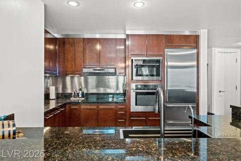 Kitchen featuring recessed lighting, under cabinet range hood, dark stone countertops, and stainless steel appliances Kitchen featuring recessed lighting, under cabinet range hood, dark stone countertops, and stainless steel appliances