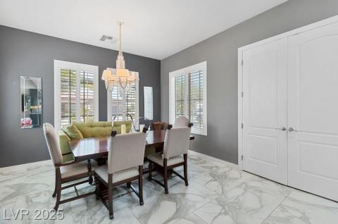 Dining space with light marble finish floors, plenty of natural light, and a chandelier