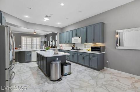 Kitchen featuring light marble finish flooring, stainless steel appliances, a ceiling fan, a center island, and recessed lighting