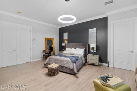 Bedroom with light wood-style flooring, crown molding, and a closet
