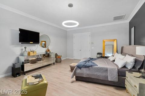 Bedroom with crown molding, wood finished floors, and a closet