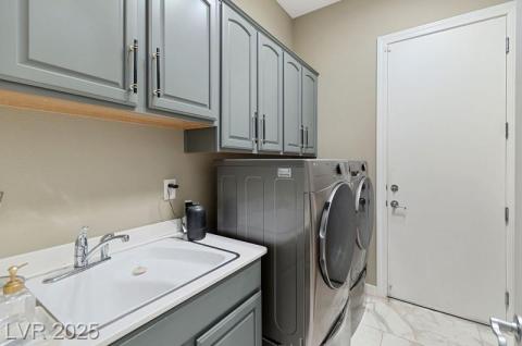 Laundry area with washing machine and clothes dryer, cabinet space, and light marble finish floors