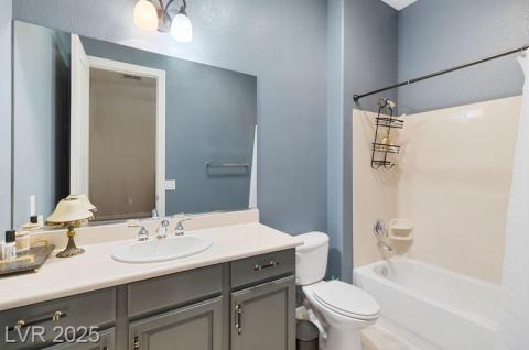 Bathroom featuring shower / bath combination with curtain, vanity, and a textured wall