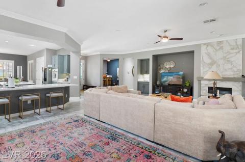 Living area with ceiling fan, ornamental molding, a fireplace, and recessed lighting