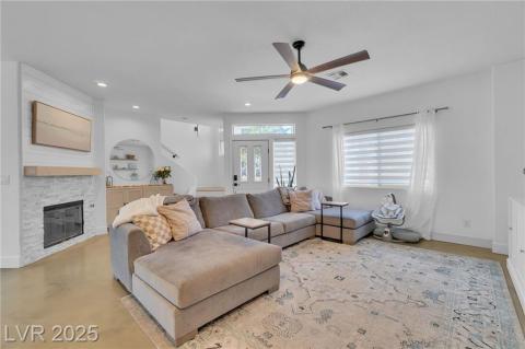 Living area featuring a stone fireplace, custom mantle, a ceiling fan, recessed lighting, and concrete floors