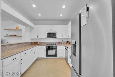 Kitchen featuring black & stainless steel appliances, white cabinetry, recessed lighting, open shelves, and light stone counters
