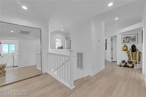 Corridor with an upstairs landing, recessed lighting, light wood-style flooring, and plenty of natural light
