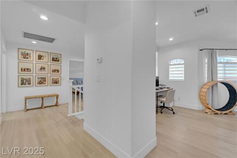 Hallway featuring an upstairs landing with light wood-type flooring, an office area, and recessed lighting.