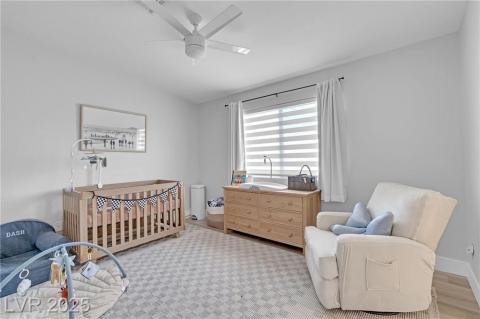 Bedroom with a crib, a ceiling fan, and wood finished floors