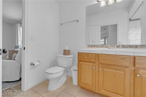 Full bath with light tile patterned flooring, vanity, tiled shower, and healthy amount of natural light