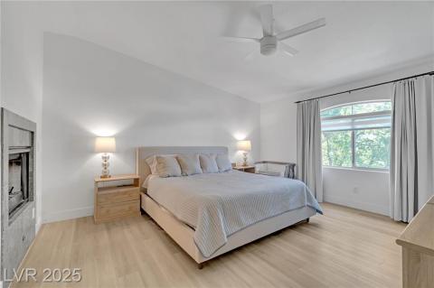 Primary Bedroom with light wood-style flooring, lofted ceiling, and a ceiling fan