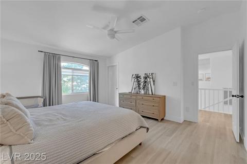 Bedroom with light wood finished floors, lofted ceiling, and a ceiling fan