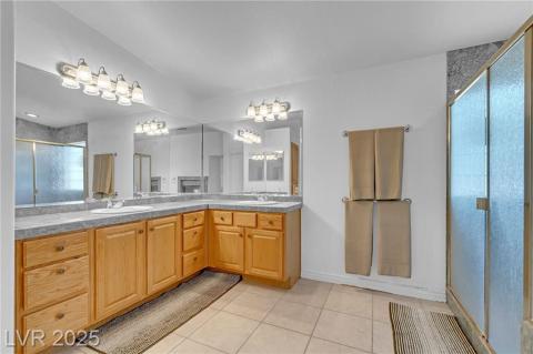 Full bathroom with double vanity, light tile patterned floors, a shower stall, and a chandelier