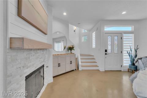 Foyer featuring finished custom stained concrete flooring, a fireplace, recessed lighting, and stairway