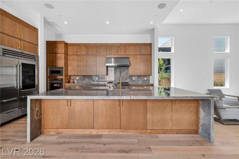 Kitchen with quartzite counter top/island, modern cabinets, a large island, a high ceiling, and backsplash Kitchen with quartzite counter top/island, modern cabinets, a large island, a high ceiling, and backsplash