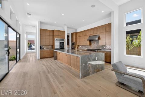 Kitchen featuring quartzite counters, a large island, upgraded modern cabinets, wood finish cabinetry, and luxury wood plank flooring Kitchen featuring quartzite counters, a large island, upgraded modern cabinets, wood finish cabinetry, and luxury wood plank flooring