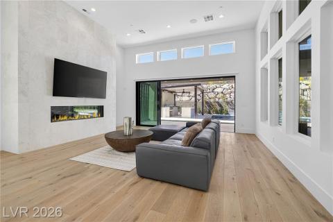 Family room featuring a 6ft linear fireplace w/remote, recessed lighting, luxury wood plank flooring, and a high ceiling Family room featuring a 6ft linear fireplace w/remote, recessed lighting, luxury wood plank flooring, and a high ceiling