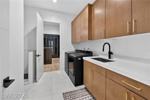 Laundry area featuring cabinet space, luxury wood plank flooring, washer and dryer, sink and recessed lighting Laundry area featuring cabinet space, luxury wood plank flooring, washer and dryer, sink and recessed lighting