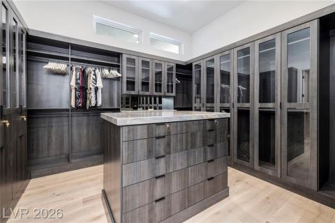 Primary custom walk in closet featuring luxury wood plank floors & quartz countertop Primary custom walk in closet featuring luxury wood plank floors & quartz countertop