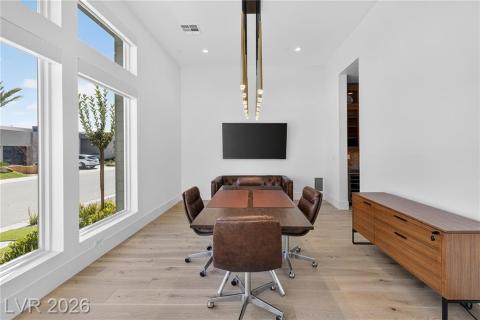 Dining Room featuring a high ceiling, luxury wood plank flooring, and designer RH lighting fixture Dining Room featuring a high ceiling, luxury wood plank flooring, and designer RH lighting fixture