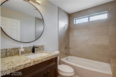 This bathroom features elegant granite counters, a tiled tub area, and a vanity for everyday convenience. This bathroom features elegant granite counters, a tiled tub area, and a vanity for everyday convenience.