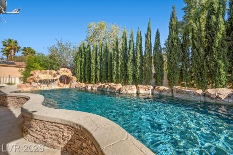 A tranquil aquatic retreat awaits, complete with rock formations and verdant privacy landscaping.