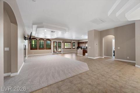 Recessed lighting illuminates an inviting open-concept living space with layered ceiling details.