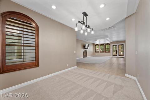 A spacious, naturally illuminated room featuring a distinctive vaulted ceiling and elegant tile flooring.