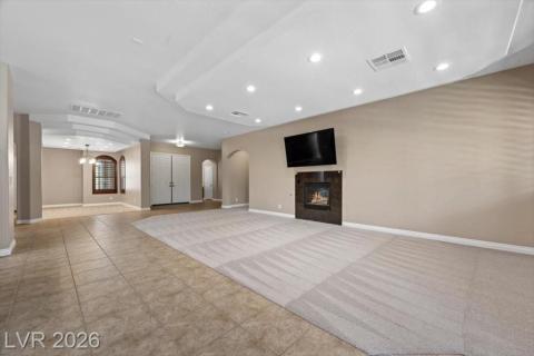 A spacious living room offers both carpet and tile flooring, highlighted by a contemporary fireplace and recessed lighting.