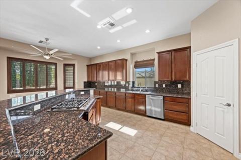 A chef's kitchen showcasing rich wood cabinetry, speckled granite countertops, and modern appliances.