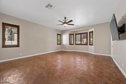 A spacious room features impressive stamped concrete flooring and elegant window shutters.
