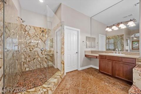 A well-lit primary bathroom featuring a spacious shower and a vanity with abundant counter space.