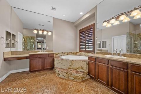 Luxurious primary bath with a corner soaking tub and individual vanities for refined comfort.