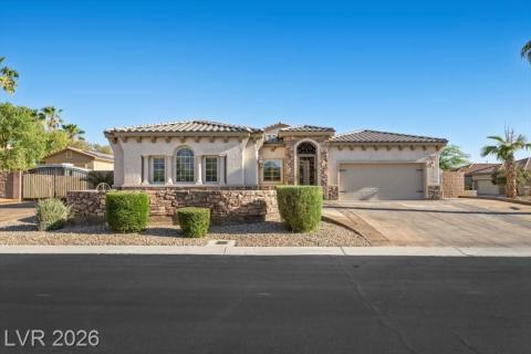 A striking stucco and stone exterior home featuring an arched entry and attached garage.