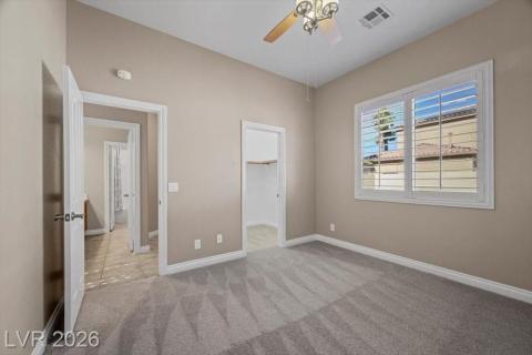 A well-lit bedroom features plush carpeting and a convenient walk-in closet.