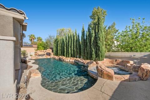 An inviting backyard oasis offers a rock-scaped pool and integrated spa, surrounded by natural landscaping.