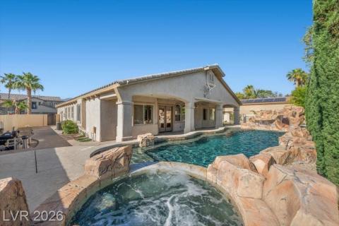 An inviting private outdoor oasis featuring a sparkling pool, bubbling spa, and a natural rock waterfall.