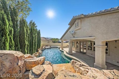 A private backyard oasis features a rock waterfall pool, perfect for serene outdoor living.