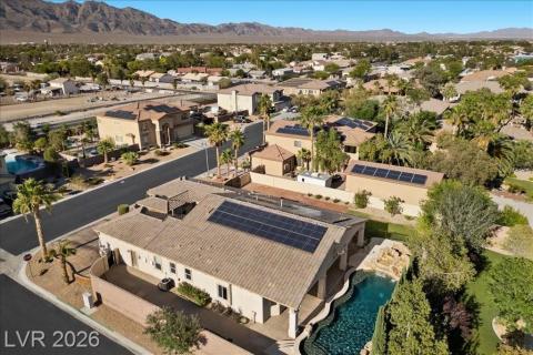 An aerial perspective reveals a desert oasis, showcasing a residence with a pool, covered patio, and mountain views.